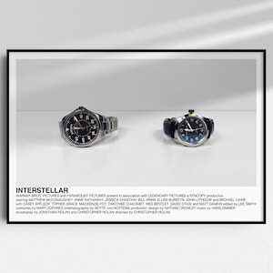 May include: Two silver wristwatches with black faces and silver bands on a white surface. The text "INTERSTELLAR" is below the watches with a description of the film's production.