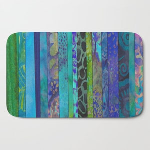 May include: A bath mat with a colorful striped pattern in shades of blue, green, and purple. The stripes are made up of different patterns and textures.