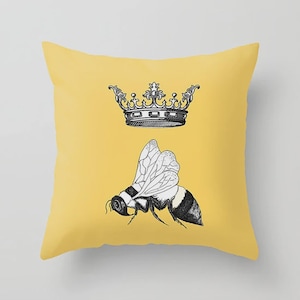 Pu&ograve; includere: Un cuscino quadrato giallo con un'illustrazione in bianco e nero di un'ape e una corona. L'ape &egrave; posizionata sotto la corona, con le ali spiegate. Il cuscino ha uno sfondo giallo pieno.