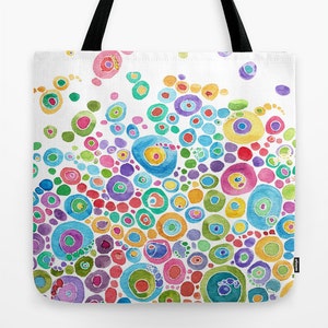 May include: A white tote bag with a colorful abstract design of overlapping circles in various shades of pink, blue, green, yellow, and purple. The circles are painted in a watercolor style, creating a vibrant and playful pattern.