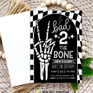 May include: A black and white birthday invitation with the text "bad 2 the bone" and a skeleton hand. The invitation includes details for Jack's 2nd birthday, with a checkered border and a white envelope.