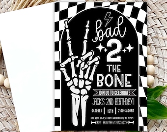 May include: A black and white birthday invitation with the text "bad 2 the bone" and a skeleton hand. The invitation includes details for Jack's 2nd birthday, with a checkered border and a white envelope.