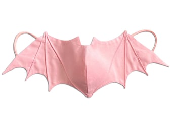 May include: Pink fabric bat wings with elastic straps for a costume.