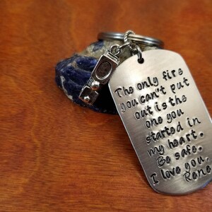 May include: Silver keychain with a small charm shaped like a fire extinguisher. The tag reads "The only fire you can't put out is the one you started in my heart. Be safe. I love you, Rone."