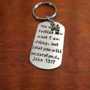 May include: Silver keychain with a cross charm and a quote from the Bible: "You don't realize what I am doing, but later you will understand. John 13:7"