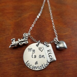 May include: Silver necklace with a charm that says "My heart is on a locomotive" and a tag that says "Rich". The necklace also has a small train charm and a heart charm.