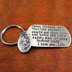 May include: Silver keychain with a guardian angel charm and a tag that reads "State Trooper 441 May God protect & shield you from harm and bring you home safely into my arms Forever yours, I love you, Lili"