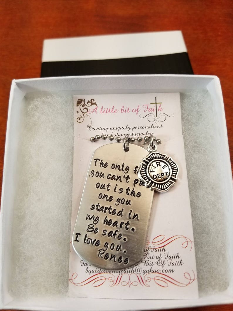 May include: A silver necklace with a dog tag pendant that reads "The only fire you can't put out is the one you started in my heart. Be safe. I love you, Renee." The dog tag is attached to a silver chain with a small silver charm that reads "Fire Dept."