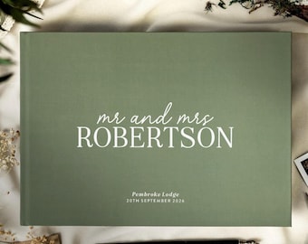 May include: A sage green rectangular guest book with white text that reads mr and mrs ROBERTSON, followed by the smaller text Pembroke Lodge 20TH SEPTEMBER 2026. The cover has a smooth matte finish and is centered horizontally on the frame.
