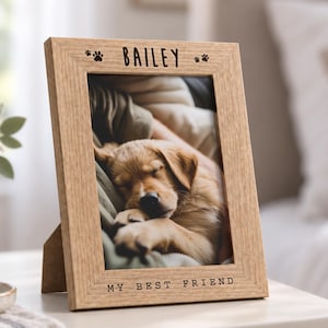 May include: A light brown wooden picture frame with a vertical orientation. The top of the frame is engraved with the name BAILEY and two paw prints. The bottom of the frame is engraved with the text MY BEST FRIEND. A photo of a puppy is inside.