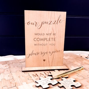 Alternative wedding guest book with this personalised wood puzzle guestbook. This rustic wedding décor feature custom jigsaw pieces, wedding table décor. Wedding sign and dried confetti, this wooden guest book is made by Secret Creation Ltd.