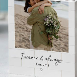 A couple embracing on a beach, with a bouquet of flowers in their hands.