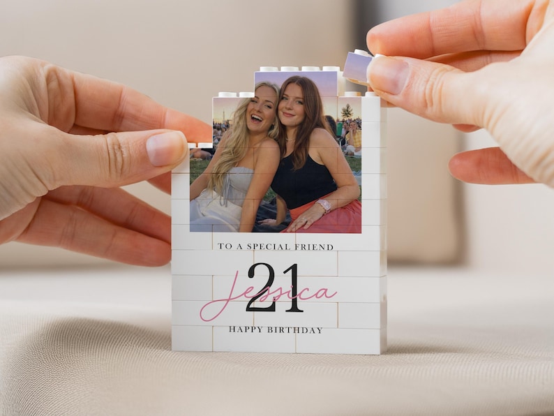 A person's hands are holding a small white card with a photo of two smiling women on it, and the text "To a special friend Jessica Happy Birthday" is written on the card.