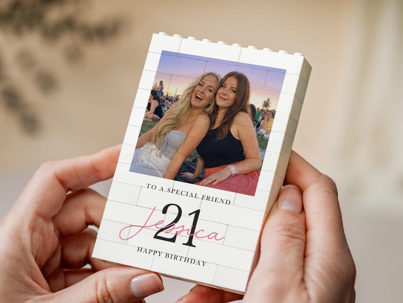 A person's hands holding a small white card with a photo of two smiling women on it. The card has text that reads "To a special friend Jessica Happy Birthday".