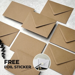 May include: A collection of rectangular brown kraft paper envelopes arranged in a scattered pattern. A circular inset shows a white envelope sealed with a small gold foil sticker. The text FREE FOIL STICKER is printed in bold black letters.