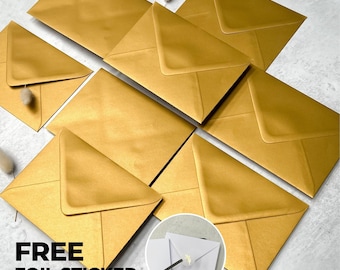 May include: A collection of metallic gold envelopes arranged in a cluster. A circular inset shows a white envelope sealed with a gold foil sticker. The text "FREE FOIL STICKER" is printed in bold black letters in the lower left corner of the image.