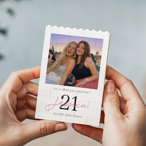 A person's hands holding a small white card with a photo of two women and text on it.