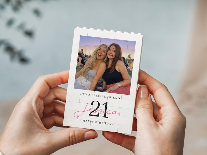 A person's hands holding a small white card with a photo of two women and text on it.