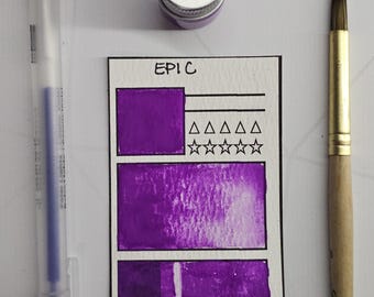 May include: A purple watercolour paint swatch card labelled "EPIC C", a purple pen, a small jar with a silver lid, and a paintbrush. The card features purple colour samples, squares, triangles, and stars.