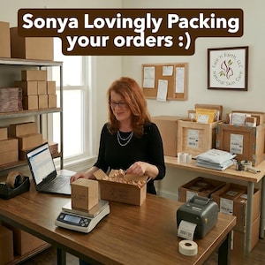 May include: A workspace featuring a person in a black long-sleeve shirt packing orders into a cardboard box. The desk includes a digital scale, a laptop, a label printer, and shipping supplies. Text at the top reads: Sonya Lovingly Packing your orders :)
