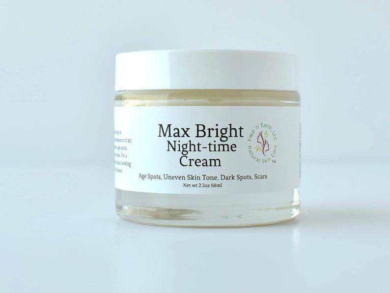 May include: A clear glass jar with a white lid containing Max Bright Night-time Cream. The label features the text Max Bright Night-time Cream, Face 'n Earth, LLC Natural Skin Care, and Age Spots, Uneven Skin Tone, Dark Spots, Scars, Net wt 2.3oz.