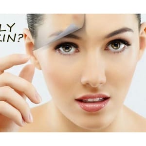 May include: A close-up of a face with a translucent film being peeled back from the forehead to reveal smoother skin underneath. The text OILY SKIN? is printed in black on the left side. The person has brown eyes and natural-toned lips.