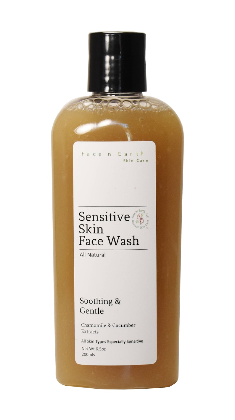 May include: A clear plastic bottle filled with a brownish, translucent liquid face wash. The white label reads Face n Earth Skin Care, Sensitive Skin Face Wash, All Natural, Soothing & Gentle, Chamomile & Cucumber Extracts, Net Wt 6.5oz.