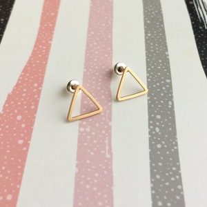Puede incluir: Un par de pendientes de tri&aacute;ngulo dorado con un dise&ntilde;o simple y minimalista. Los pendientes est&aacute;n hechos de un alambre delgado y tienen una forma geom&eacute;trica delicada.
