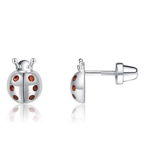 May include: A pair of silver ladybug stud earrings with red gemstone accents.