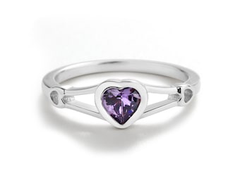 May include: A silver ring with a heart-shaped purple gemstone. The ring has two open heart shapes on either side of the gemstone.