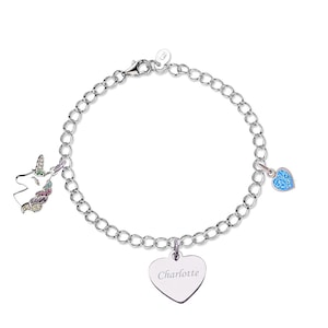 May include: A silver-toned chain bracelet featuring three charms: a unicorn head with multicolored accents, a small light blue heart-shaped crystal, and a larger heart-shaped pendant engraved with the name Charlotte in a cursive script font.