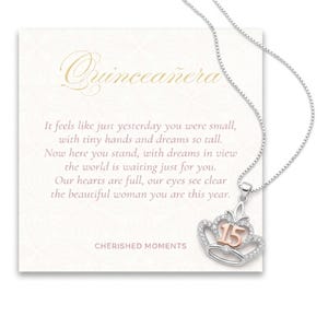 May include: A silver necklace with a crown pendant, featuring the number "15" in rose gold. The pendant is adorned with clear crystals. The necklace is displayed on a card with the word "Quinceañera" and a poem.