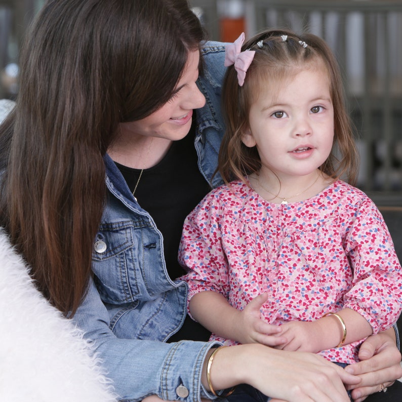 Mother and daughter both wearing 14K gold plated bangles for baby, toddler, child and adult.