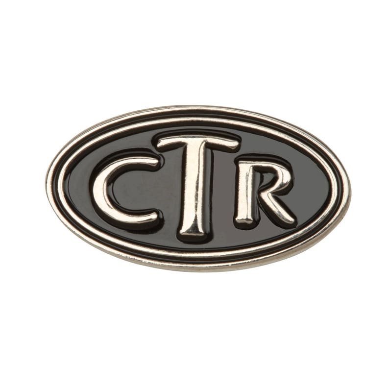 Puede incluir: Un pin ovalado plateado con fondo de esmalte negro y las letras CTR en blanco.