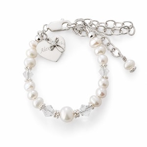 May include: A silver-toned bracelet featuring white freshwater pearls and clear faceted crystal beads. The bracelet includes a heart-shaped silver charm engraved with the name Alexandra and a small cross accent, finished with a lobster clasp closure.