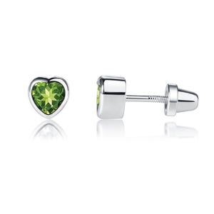 May include: A pair of heart-shaped stud earrings featuring a faceted green peridot gemstone set in a polished silver-tone metal frame. The earrings include a threaded post and a matching screw-back closure for a secure fit on the earlobe.