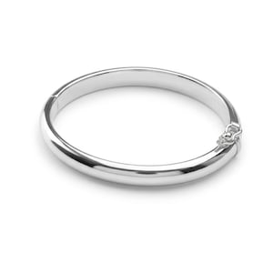 Może przedstawiać: Polerowana bransoletka typu bangle w kolorze srebrnym o gładkiej, zaokrąglonej powierzchni z bezpiecznym zapięciem na zawiasie z jednej strony. Bransoletka ma ciągły, okrągły kształt z odblaskowym wykończeniem i solidną metalową konstrukcją.