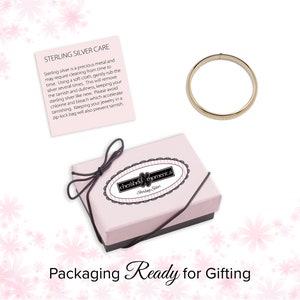 Care information card. 14K gold plated bangle. Pink storage and gift box with black elastic bow ready for gifting.