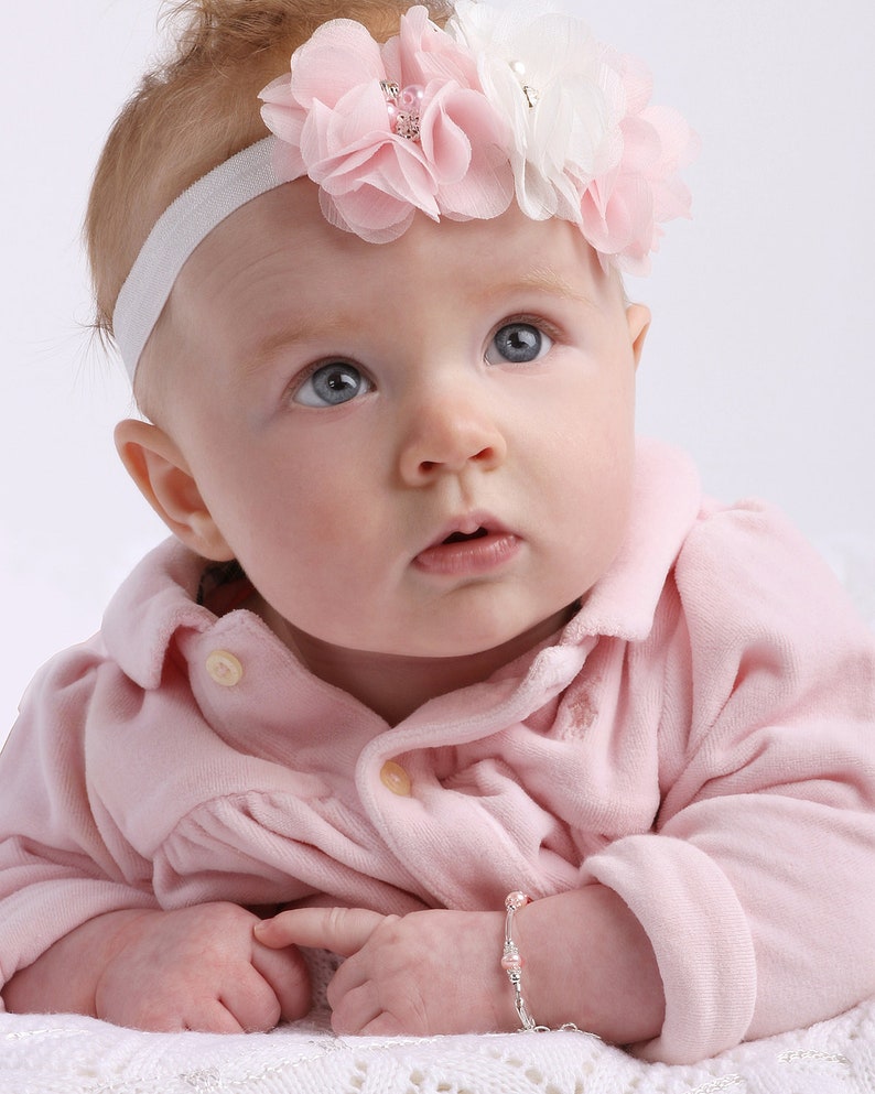 Baby girl wearing sterling silver bracelet with long silver beads and pink pearl accents.