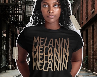 May include: A black t-shirt with the word "MELANIN" repeated four times in a gradient of brown shades. The text is written in a handwritten style.