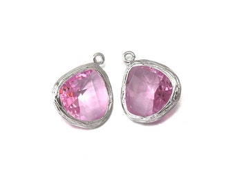 Puede incluir: Dos colgantes de plata con piedras de cristal rosa. Los colgantes tienen un diseño texturizado y orgánico.