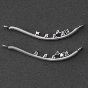 May include: Two silver curved bar pendants with small clear diamonds set in a staggered pattern.