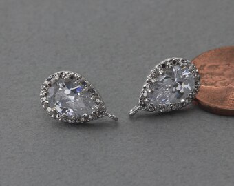 May include: Two silver teardrop-shaped earring charms with clear crystal stones and a halo of smaller stones. The charms have a loop at the top for attaching to earrings.