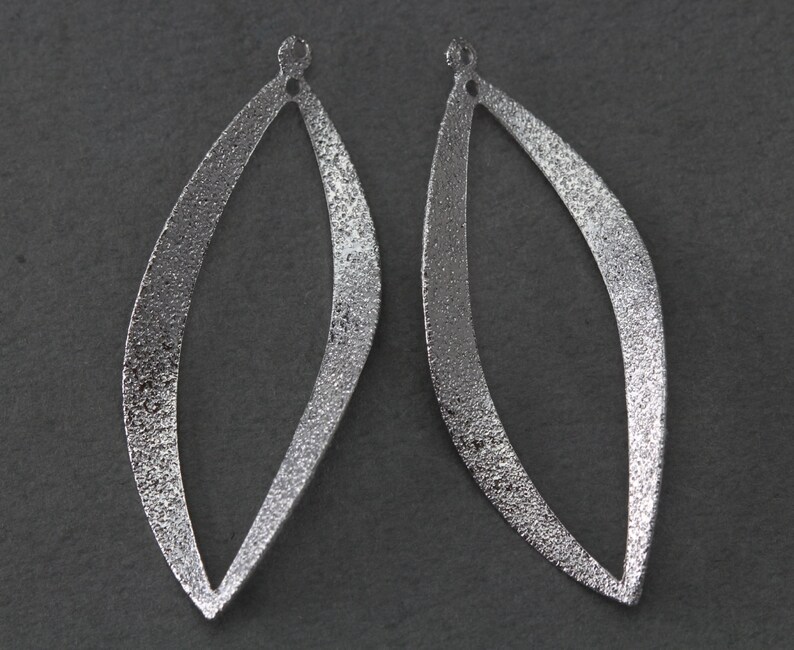 May include: A pair of silver-toned metal earrings shaped like leaves with a textured finish.