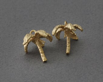 May include: Two gold-colored palm tree charms with a loop at the top for attaching to jewelry or other crafts.