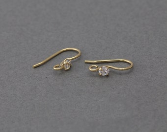 May include: Two gold earring hooks with a small clear crystal at the end of each hook.