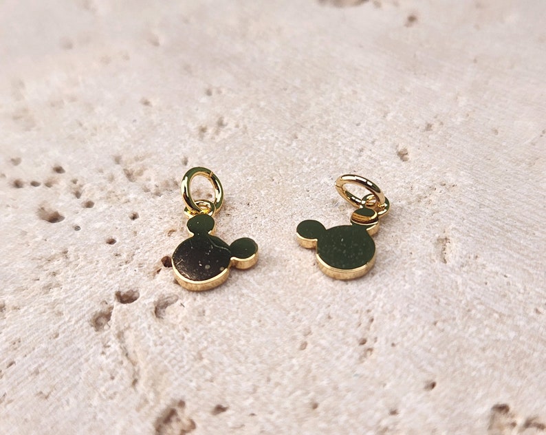 May include: Two gold-colored Mickey Mouse head charms with a loop for attaching to a necklace or bracelet.