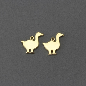 May include: Two gold-colored metal charms shaped like geese. The charms are flat and have a hole at the top for attaching to a necklace or bracelet.