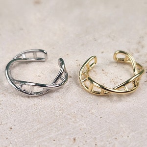 May include: Two ear cuffs, one silver and one gold, in a twisted, ladder-like design.