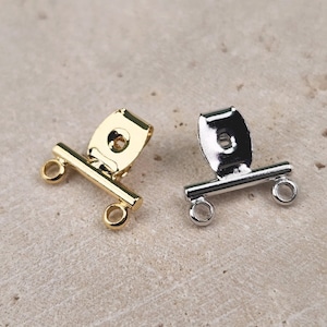 May include: Two metal jewelry clasps, one gold and one silver, with a bar and two loops. The clasps are used for connecting jewelry pieces.
